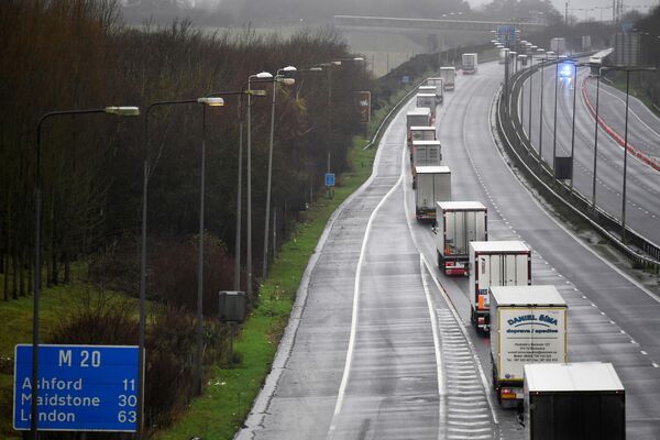 Por temor a quedarse varados en la frontera, los conductores se niegan a viajar de la Unión Europea al Reino Unido. Y este hecho ya es el presagio de un posible desastre: la vacuna contra el coronavirus se suministra desde Bélgica, más de la mitad de todas las frutas y verduras en las tiendas también proviene de la UE.En la foto: la caravana de camiones bajo escolta de la Policía circula por la ruta M20 hacia Londres. - Sputnik Mundo