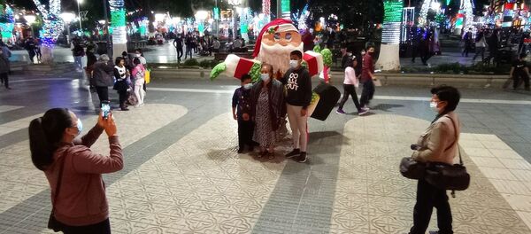 Familias sacándose fotos junto a un muñeco de Papa Noel, en la plaza 14 de Septiembre - Sputnik Mundo