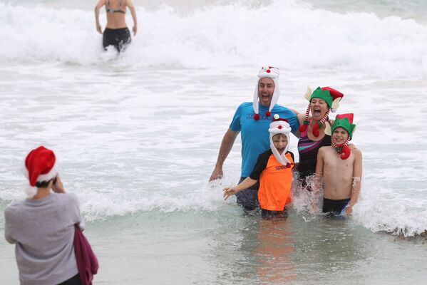 Una familia se toma fotos con gorros navideños en una playa en Sydney, Australia.  - Sputnik Mundo