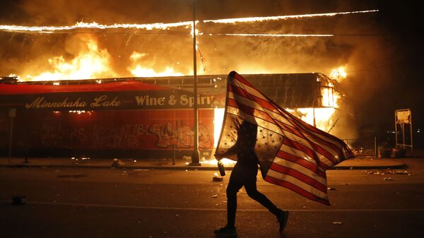 Un manifestante porta la bandera de EEUU durante las protestas por la muerte de George Floyd, el 28 de mayo del 2020 (Imagen referencial) - Sputnik Mundo