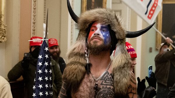 Jake Angeli, con su sombrero característico y una bandera de EEUU, durante el asalto al Capitolio del 6 de enero de 2021 - Sputnik Mundo