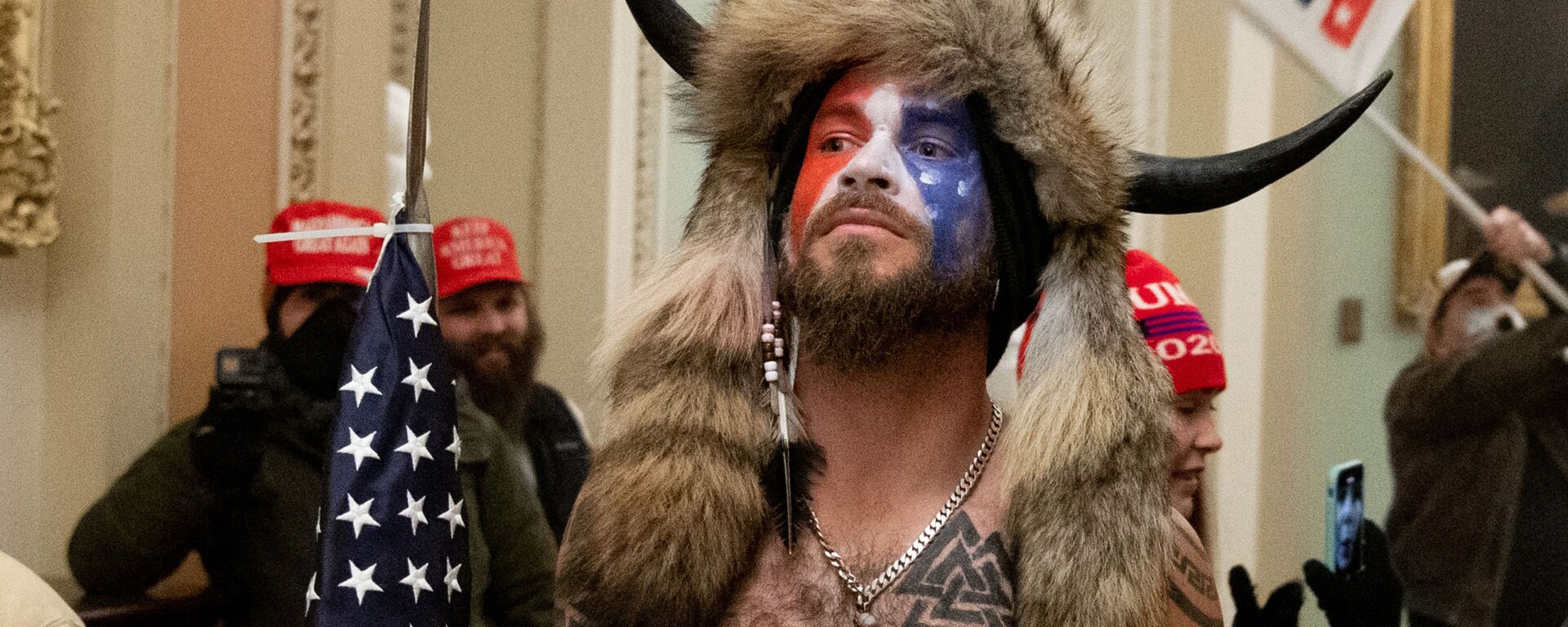 Jake Angeli, con su sombrero característico y una bandera de EEUU, durante el asalto al Capitolio del 6 de enero de 2021 - Sputnik Mundo, 1920, 07.01.2023