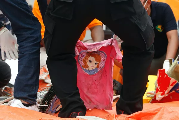 Rescatistas indonesios manipulan una camiseta rosada encontrada durante las operaciones de búsqueda en el mar de Java. - Sputnik Mundo
