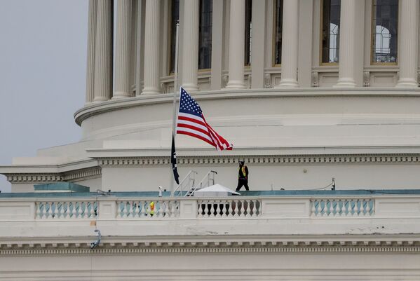 Un empleado del Capitolio camina cerca de una bandera estadounidense días después de que un grupo de partidarios del presidente de Estados Unidos, Donald Trump, irrumpiera en el edificio. - Sputnik Mundo