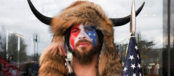  Jake Angeli, con su sombrero característico y una bandera de EEUU, durante el asalto al Capitolio del 6 de enero de 2021 - Sputnik Mundo