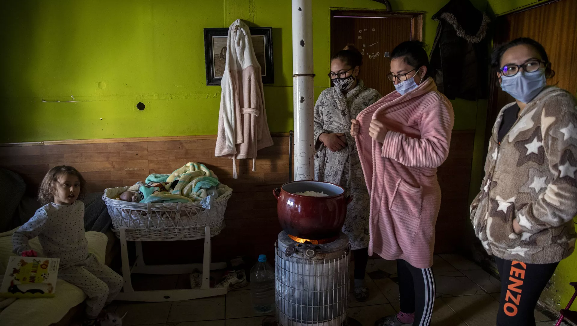 Los familiares del niño Jesús Fernández, de un mes de edad, derriten nieve en una olla en el barrio Cañada Real. Madrid, 12 de enero de 2021.