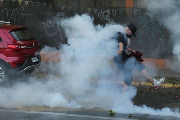 El incidente ocurrió el 5 de febrero. Un vídeo, en el que un uniformado realiza varios disparos contra el malabarista callejero Francisco Martínez luego de que este se negara a seguir sus órdenes, se viralizó en las redes. En la foto: un manifestante empuja una bomba lacrimógena lanzada por la Policía.  - Sputnik Mundo