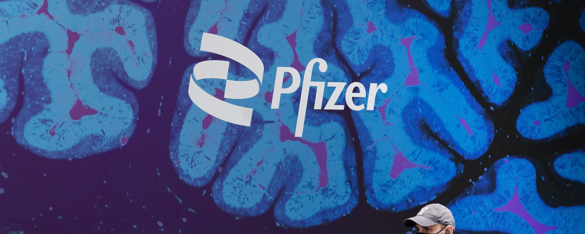 Un hombre camina frente a un logo del laboratorio de Pfizer frente a la sede del laboratorio en Nueva York - Sputnik Mundo, 1920, 25.02.2021