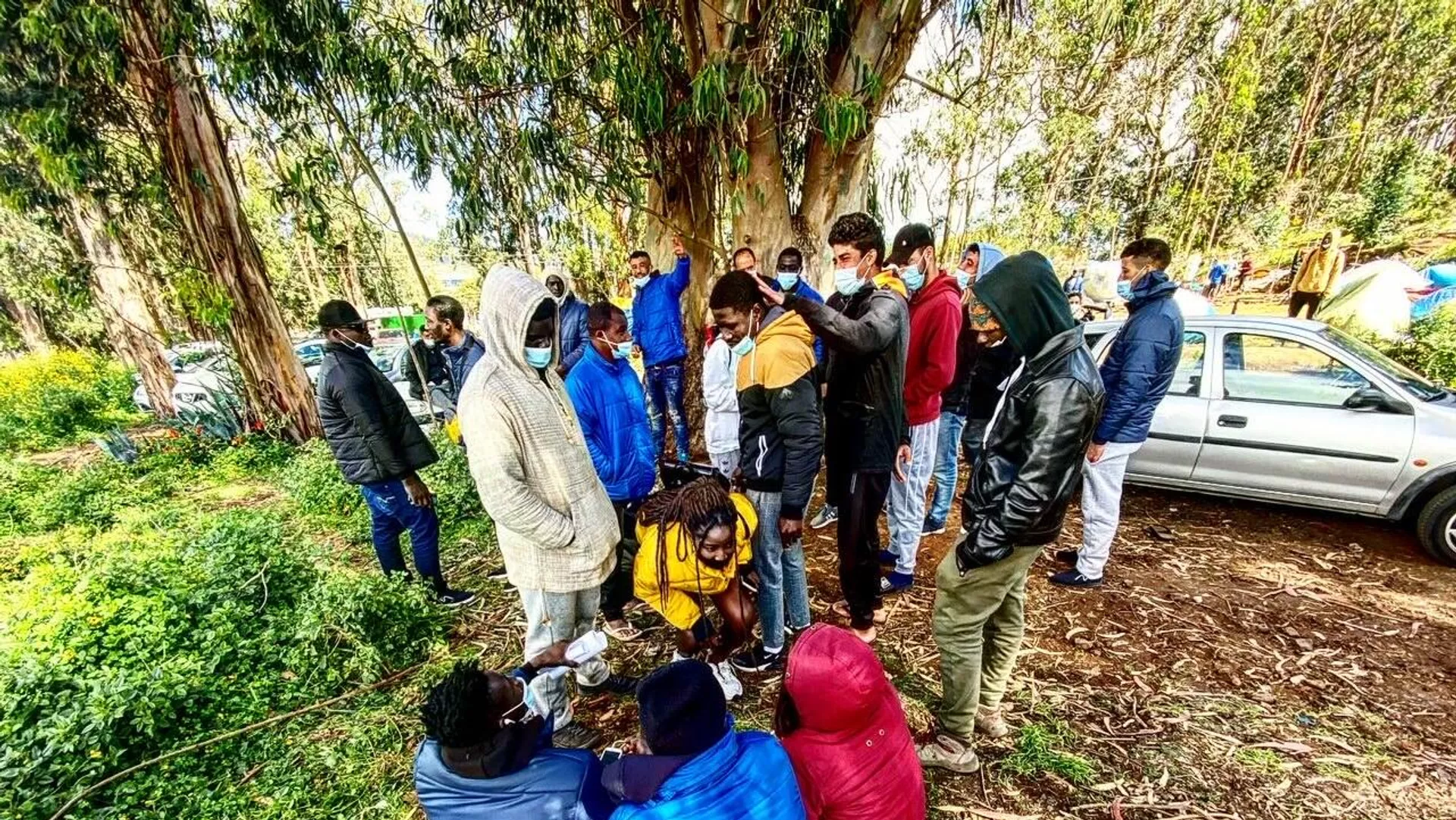 Varios inmigrantes esperan frente al campamento de Las Raíces, en Tenerife