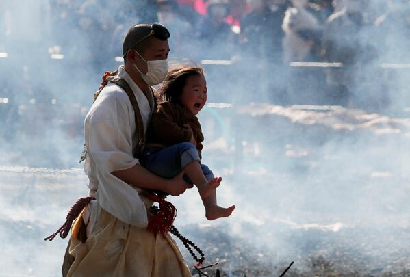 Un monje budista lleva a un bebé que llora en una tradicional caminata sobre brasas ardientes Hiwatari Matsuri en Tokio, Japón. - Sputnik Mundo