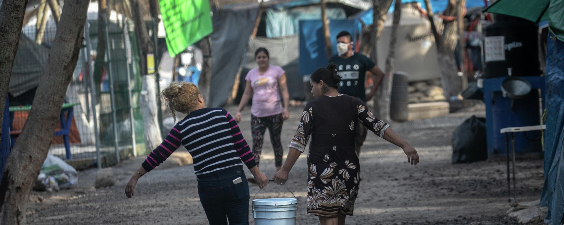 Los solicitantes de asilo en Estados Unidos llevan agua dulce distribuida en un campamento de migrantes en la frontera entre EEUU y México - Sputnik Mundo, 1920, 24.03.2021