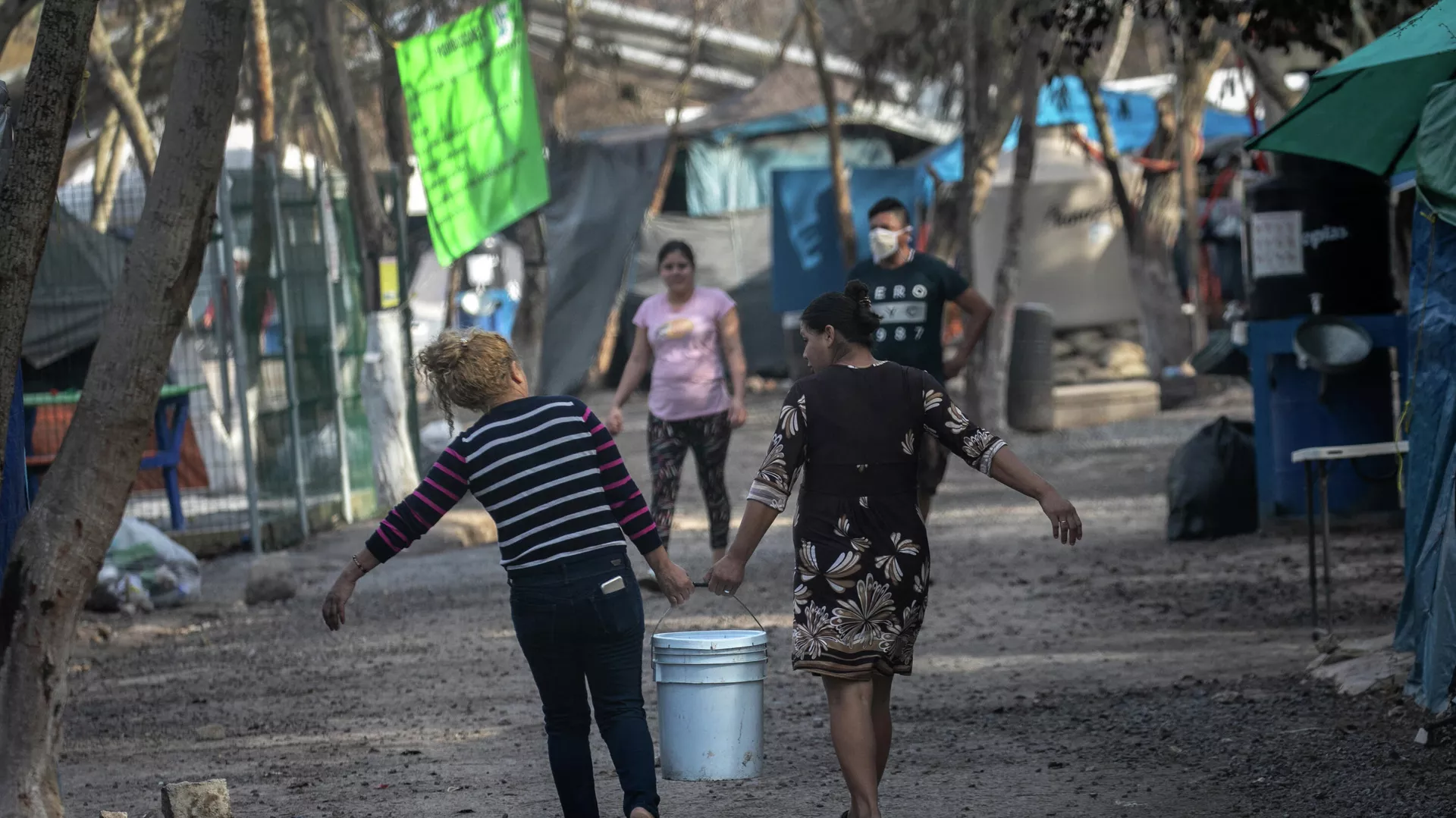 Los solicitantes de asilo en Estados Unidos llevan agua dulce distribuida en un campamento de migrantes en la frontera entre EEUU y México Los solicitantes de asilo en Estados Unidos llevan agua dulce distribuida en un campamento de migrantes en la frontera entre EEUU y México - Sputnik Mundo, 1920, 24.03.2021