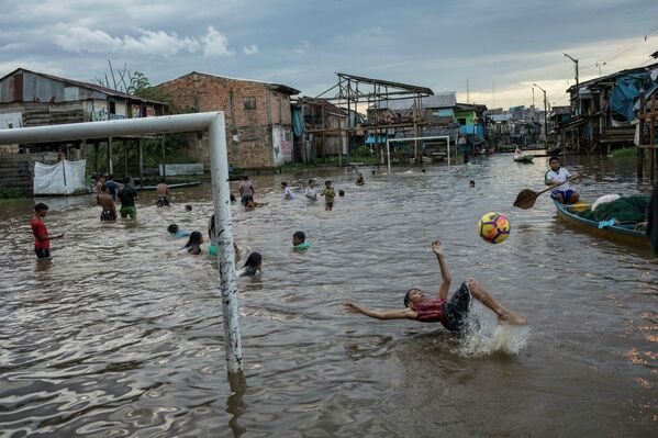 Unos niños juegan en un distrito inundado de la ciudad de Iquitos, en Perú. - Sputnik Mundo