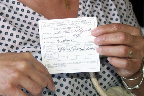 Estomatóloga Aida Martínez  muestra su tarjeta de vacunación - Sputnik Mundo