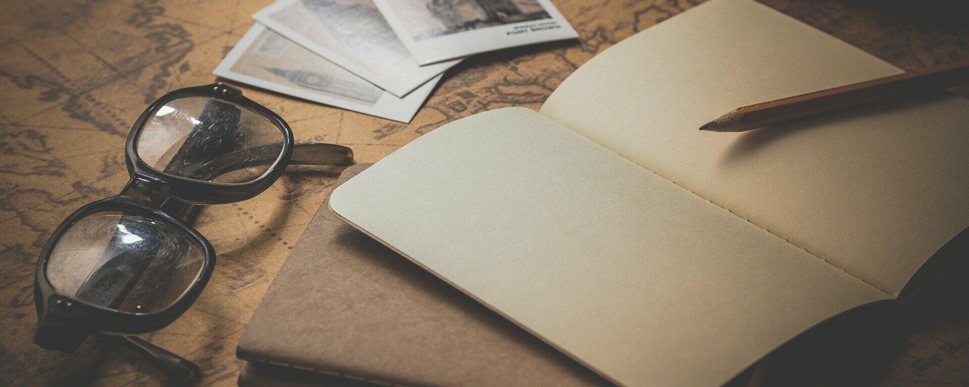 Unos lentes y un libro sobre un mapa. Imagen referencial - Sputnik Mundo, 1920, 07.04.2021