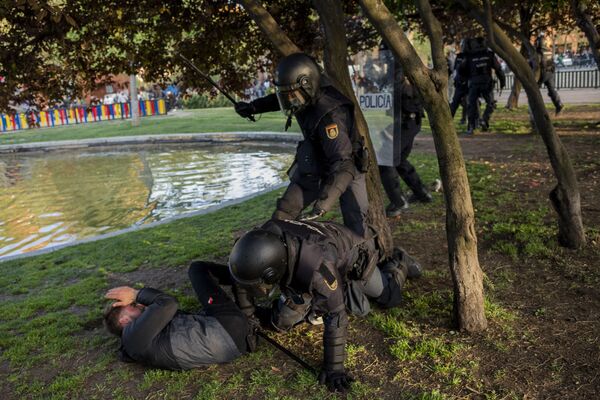 Unos 200 agentes de policía custodiaron el acto, que fue convocado como una concentración pacífica, pero terminó con altercados.En la imagen, un agente golpea a uno de los manifestantes. La jornada terminó con varios detenidos y más de una decena de personas atendida por los servicios de emergencia sanitaria después de que se lanzaran objetos y disturbios por las inmediaciones. - Sputnik Mundo