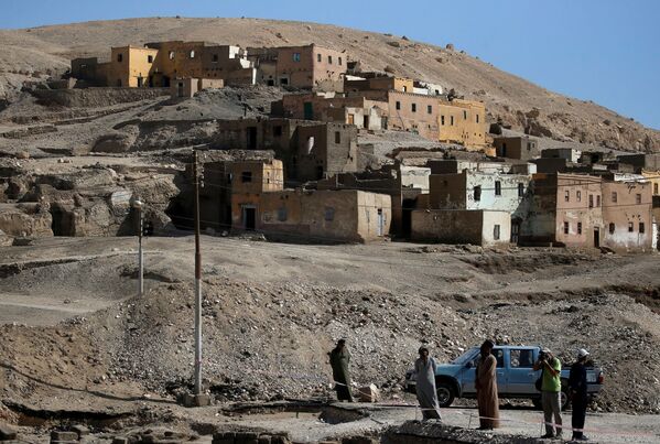 Unas personas al lado de la aldea de Al-Qarna cerca de los colosos de Memnón —no figuran en la foto—, las ruinas de dos estatuas de piedra que custodiaban el templo mortuorio construido para el faraón Amenhotep III. - Sputnik Mundo