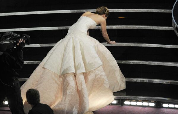 El blanco de los memes en la premiación del año siguiente fue Jennifer Lawrence, pues se cayó al subir las escaleras del escenario para recibir su Óscar a la mejor actriz. La probable razón de su resbalón fue la larga cola de su vestido Dior. El atuendo, cuya etiqueta de precio alcanzaba los cuatro millones de dólares, es el más caro que haya cruzado la alfombra roja del premio cinematográfico. - Sputnik Mundo