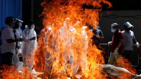 Familiares de un fallecido a causa del coronavirus en una pira funeraria de Nueva Delhi, la India. - Sputnik Mundo