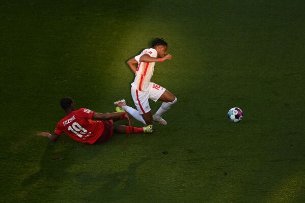 El defensor holandés del Colonia, Kingsley Ehizibue, y el centrocampista francés del Leipzig, Christopher Nkunku, disputan el balón durante un partido de la Bundesliga, la primera división del fútbol alemán. - Sputnik Mundo