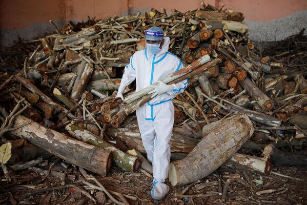 Los crematorios no dan abasto con el número de muertos: los hornos se derriten por el funcionamiento ininterrumpido y han empezado a montar hogueras funerarias en las calles, aparcamientos y espacios abiertos.En la foto: un hombre cargando leña para una cremación masiva en Nueva Delhi. - Sputnik Mundo