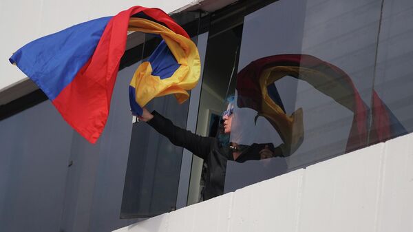 Una mujer saca una bandera de Colombia por la ventana durante las protestas en Colombia - Sputnik Mundo