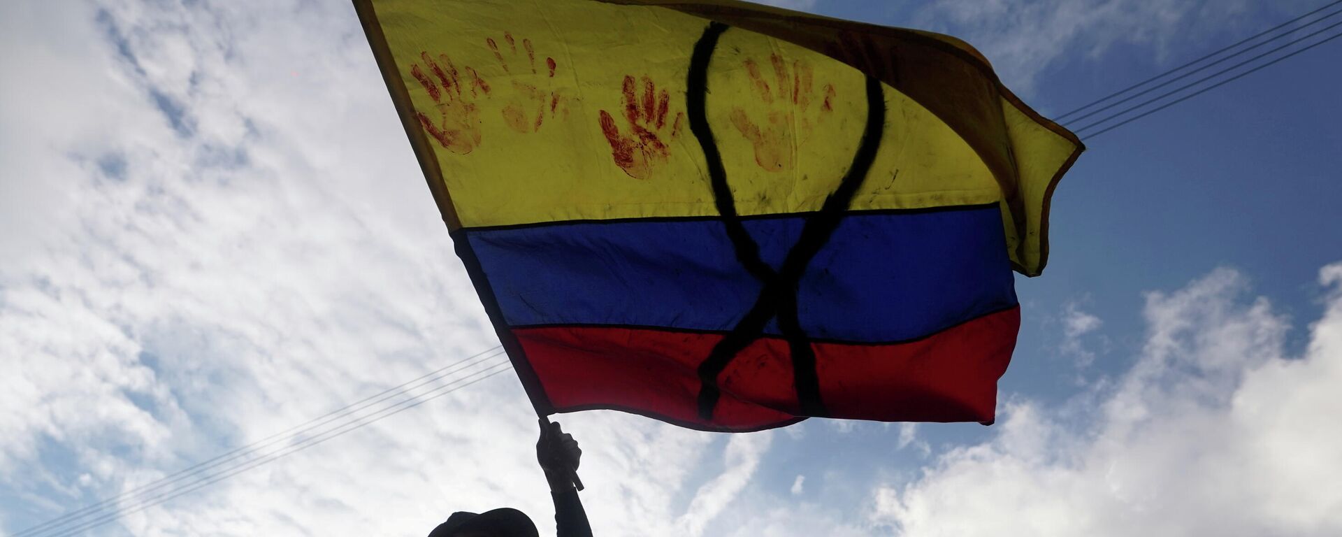 Un manifestante con una bandera de Colombia con un lazo negro y manchas rojas - Sputnik Mundo, 1920, 31.05.2021