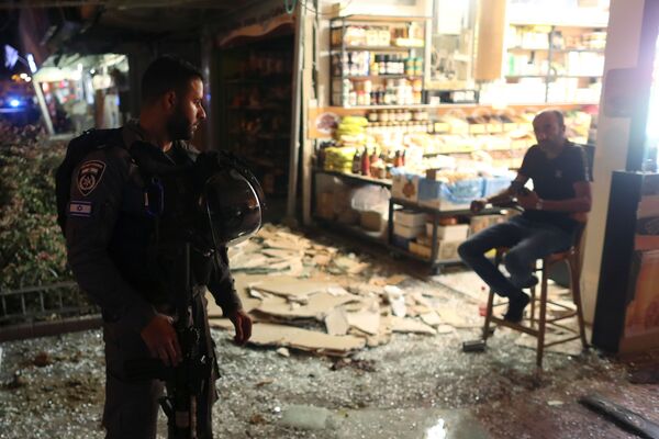 Un funcionario de seguridad israelí habla con un testigo del impacto de un cohete palestino en Holon.  - Sputnik Mundo