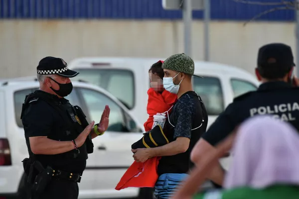 La cifra total de menores de edad es de unos 1.500 niños, informó el Ministerio del Interior de España.En la foto: un policía junto a un hombre migrante que sostiene en sus brazos a una niña en la playa del Tarajal. La cifra total de menores de edad es de unos 1.500 niños, informó el Ministerio del Interior de España.En la foto: un policía junto a un hombre migrante que sostiene en sus brazos a una niña en la playa del Tarajal. - Sputnik Mundo