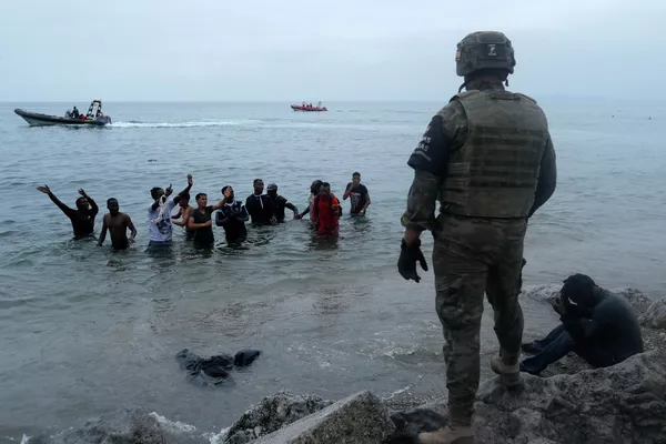 Efectivos del Ejército, junto a las Policías de ámbito nacional y local, están patrullando las calles de la ciudad y controlando los puntos más sensibles.En la foto: un oficial español se para frente a unos migrantes, después de que miles de personas provenientes de Marruecos cruzaran la frontera entre los países. Efectivos del Ejército, junto a las Policías de ámbito nacional y local, están patrullando las calles de la ciudad y controlando los puntos más sensibles.En la foto: un oficial español se para frente a unos migrantes, después de que miles de personas provenientes de Marruecos cruzaran la frontera entre los países. - Sputnik Mundo