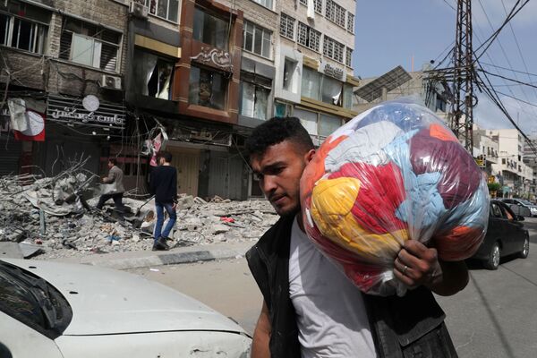 El 20 de mayo, el gabinete de seguridad del primer ministro de Israel, Benjamin Netanyahu, aprobó un alto el fuego unilateral. En la foto: un palestino pasa frente a unos edificios bombardeados por Israel. - Sputnik Mundo