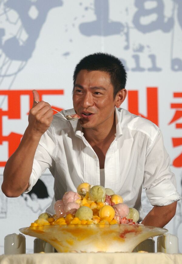 La historia del helado empezó hace unos 3.000 años en China, en donde se elaboraban refrescos con una mezcla de hielo, nieve y trozos de fruta.En la foto: el actor y cantante chino, Andy Lau, se come un helado durante una sesión fotográfica en Taipéi, en 2005. - Sputnik Mundo