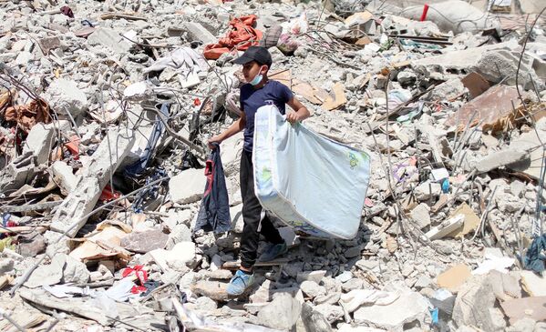 Según  el director regional del Comité Internacional de la Cruz Roja, Fabrizio Carboni, los palestinos tardarán años en reconstruir las casas que fueron destruidas y mucho más tiempo para normalizar sus vidas. En la foto: un niño palestino sobre las ruinas de una  casa destruida.  - Sputnik Mundo