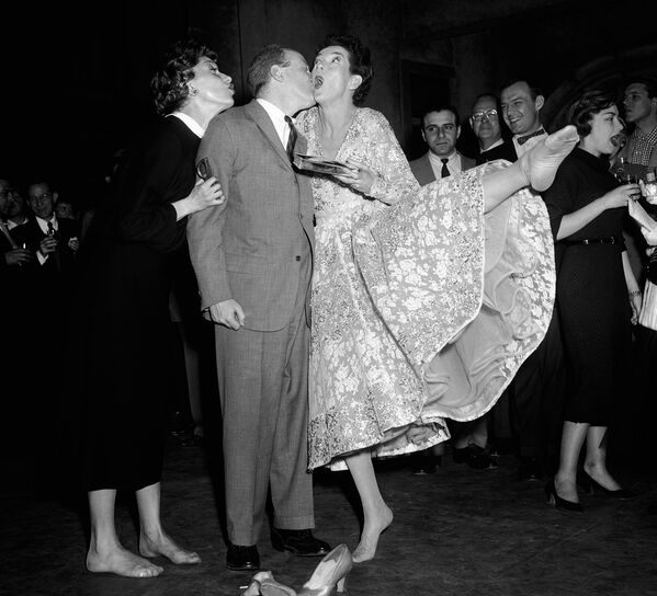 Hoy en día, un beso es para muchas personas la expresión más común de amor, cariño o afecto. Y pocos saben que existe una ciencia dedicada al estudio de los besos que se denomina filematología. En la foto: la actriz Rosalind Russell y el coproductor Robert Fryer en una fiesta de despedida con los miembros del musical Wonderful Town, Nueva York, 1954. - Sputnik Mundo
