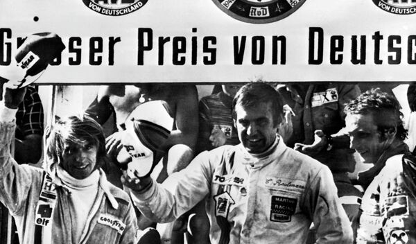 Carlos Reutemann saluda desde el podio tras consagrarse ganador del Gran Premio de Alemania de Fórmula 1, junto al francés Jacques Laffite (2º) y al austriaco Niki Lauda (3º). Nürburgring, 3 de agosto de 1975. - Sputnik Mundo