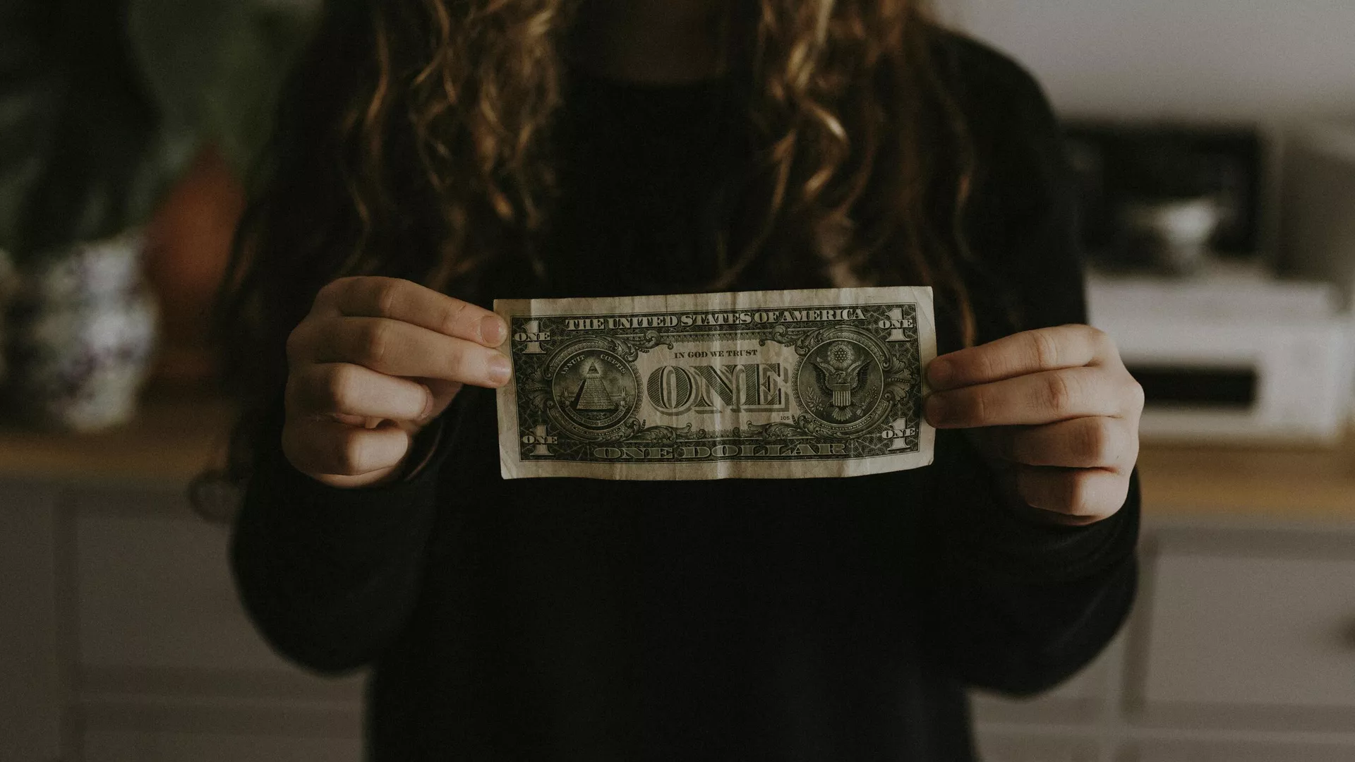 Una mujer sostiene un billete de un dólar ()