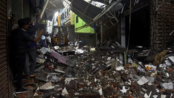 La gente usa sus teléfonos móviles para tomar fotos de un edificio derrumbado tras las lluvias en Mumbai, India, el 23 de julio de 2021 - Sputnik Mundo