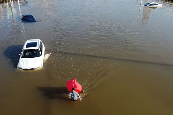 El 17 de julio fuertes lluvias azotaron la parte central de China. La provincia de Henan fue la más afectada. Algunas estaciones meteorológicas de la ciudad de Zhengzhou han registrado un récord histórico de precipitación media por día. En la foto: un hombre con un cubo de basura camina por una calle inundada en Xinxiang. - Sputnik Mundo