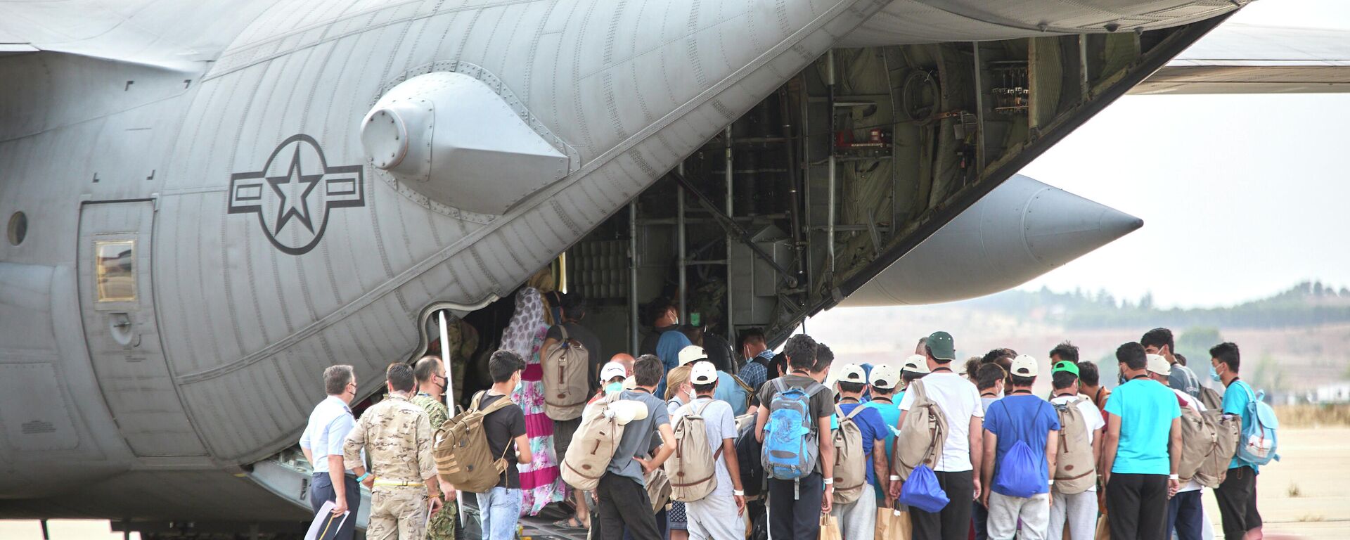 Un grupo de jóvenes y familias afganas, se dirigen a subir a un avión estadounidense para ser trasladados a Alemania, en la base aérea de Torrejón de Ardoz, a 24 de agosto de 2021, en Madrid (España).  - Sputnik Mundo, 1920, 25.08.2021