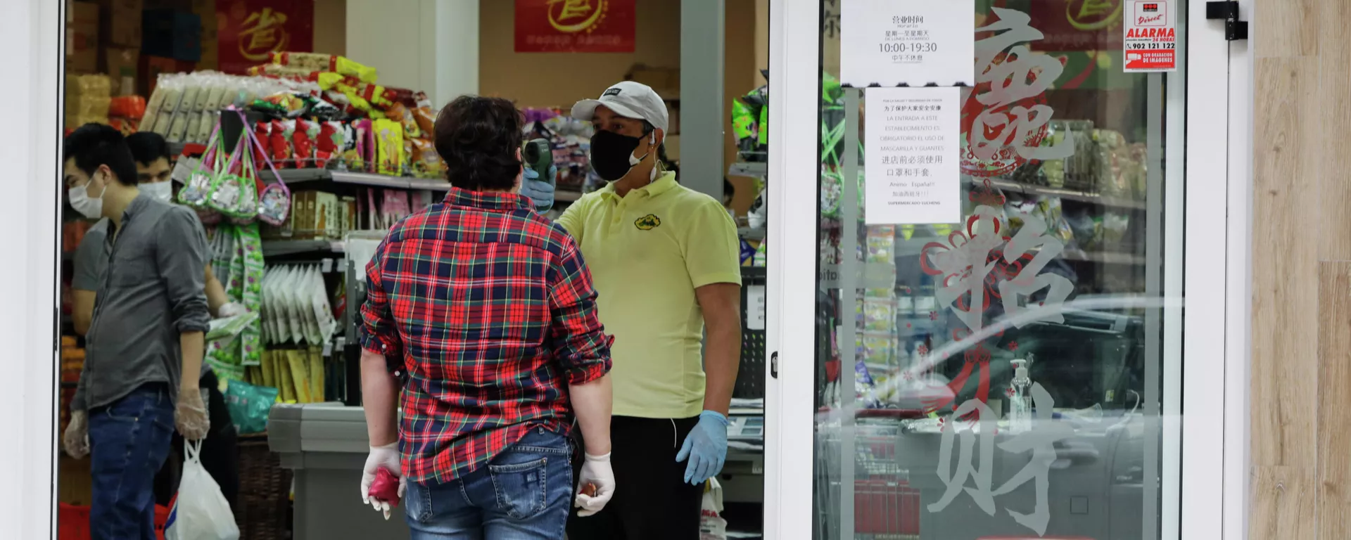 Un trabajador le toma la temperatura a un cliente a la entrada de un supermercado chino abierto en el distrito de Usera el día en el que algunos comercios chinos están volviendo a abrir en Madrid, muchos de ellos en este distrito, conocido como el Chinatown de la capital y donde en algunos casos han comenzado a realizar tomas de temperatura a sus clientes en la entrada, en Madrid (España) a 4 de mayo de 2020. - Sputnik Mundo, 1920, 25.08.2021