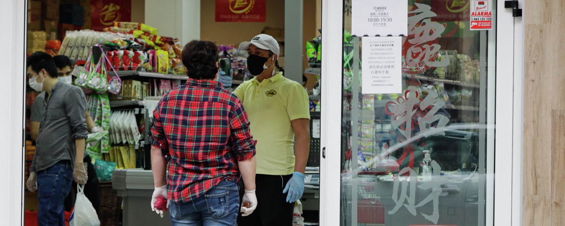 Un trabajador le toma la temperatura a un cliente a la entrada de un supermercado chino abierto en el distrito de Usera el día en el que algunos comercios chinos están volviendo a abrir en Madrid, muchos de ellos en este distrito, conocido como el Chinatown de la capital y donde en algunos casos han comenzado a realizar tomas de temperatura a sus clientes en la entrada, en Madrid (España) a 4 de mayo de 2020. - Sputnik Mundo, 1920, 25.08.2021