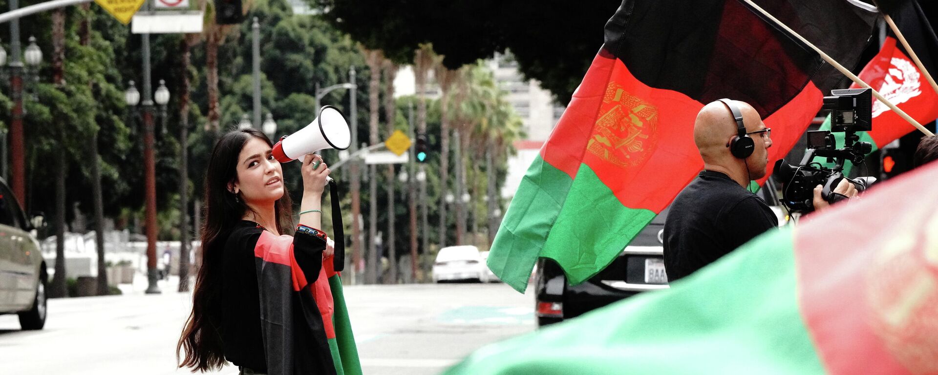 La inmigrante afgano-estadounidense Hameeda Uloomi, de 18 años, con un megáfono, en un mitin que organizó contra los talibanes y los acontecimientos en Afganistán, durante una manifestación en el centro de Los Ángeles, California, Estados Unidos, el 21 de agosto de 2021 - Sputnik Mundo, 1920, 27.08.2021