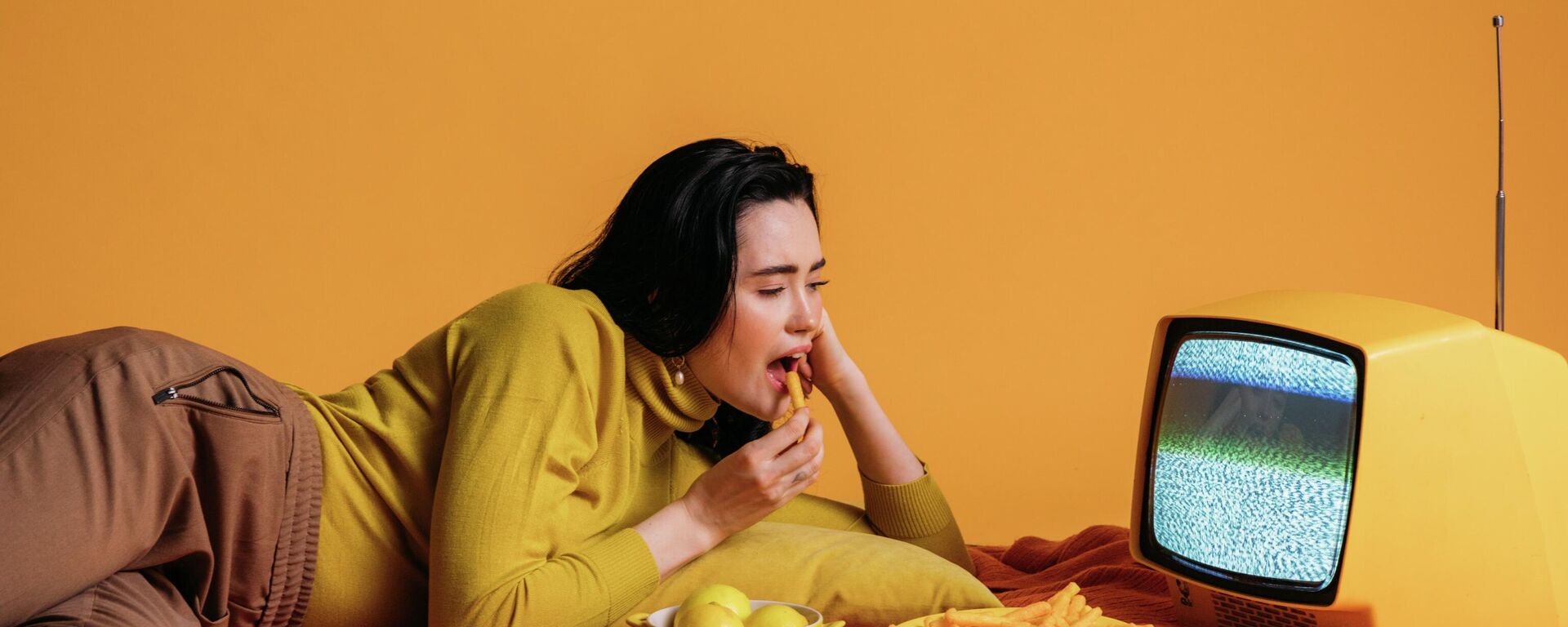 Una joven comiendo frente al televisor, imagen referencial - Sputnik Mundo, 1920, 03.09.2021