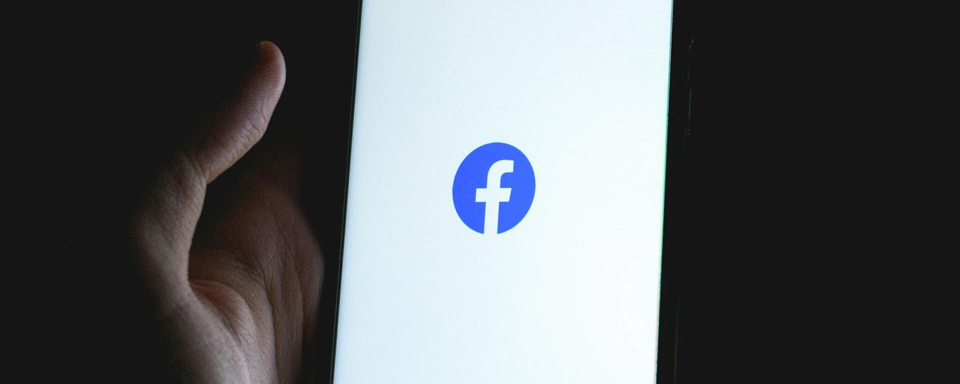 Una persona sostiene un teléfono con el logotipo de Facebook - Sputnik Mundo, 1920, 11.03.2022