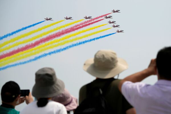 Aparte de los aviones, durante el evento también se presentarán maquetas de cohetes y naves espaciales chinas, incluido el primer satélite chino para el estudio del Sol.En la foto: unos espectadores observan el vuelo del grupo acrobático chino de la Fuerza Aérea, Red Falcon, en el Salón Aeroespacial de Zhuhai. - Sputnik Mundo