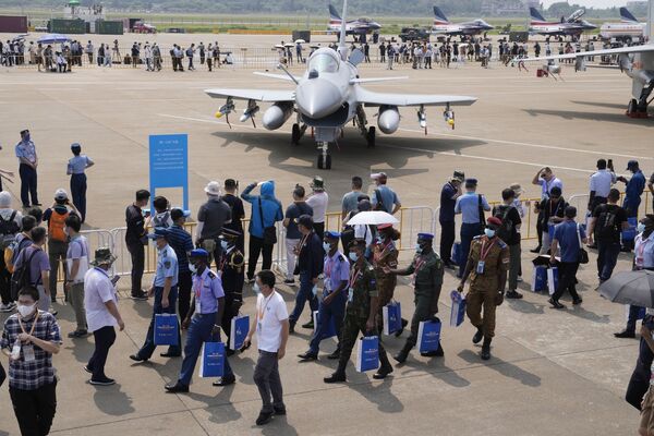 La mayor exposición en el ámbito de la aviación y espacio de China se celebra cada dos años, aunque en 2020 tuvo que ser cancelada debido a la pandemia. En la foto: militares extranjeros pasan cerca del caza ligero chino J-10C.  - Sputnik Mundo