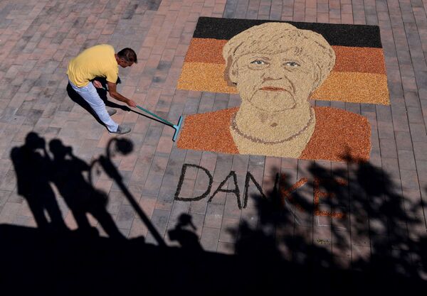El artista kosovar Alkent Pozhegu termina un retrato de la canciller alemana Angela Merkel hecho con granos y semillas. - Sputnik Mundo