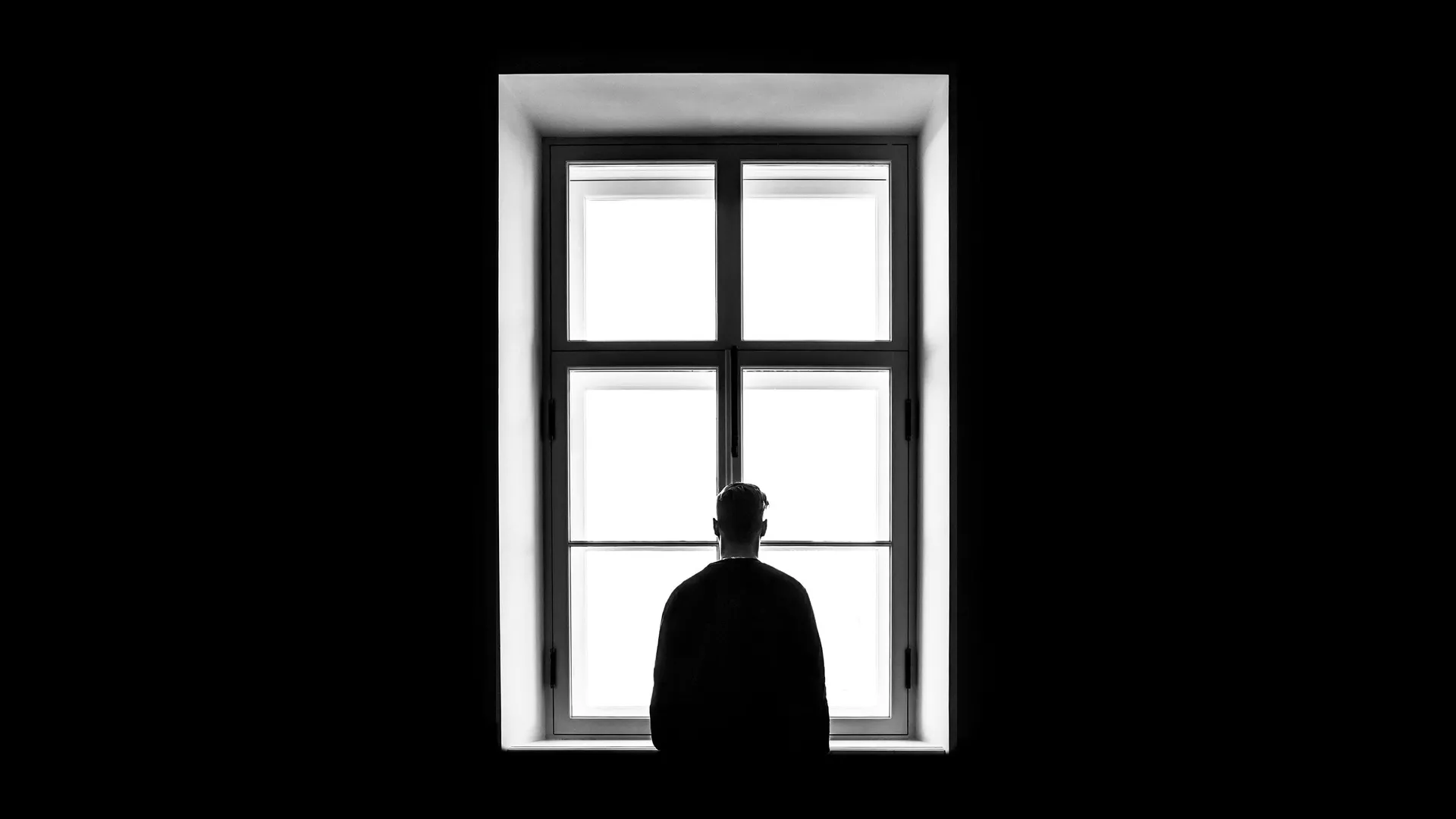 Una persona delante de una ventana en la oscuridad