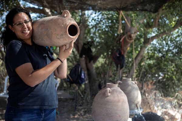 Una de las responsables de la excavación, Liat Nadav-Ziv, sostiene una jarra encontrada en el sitio. - Sputnik Mundo