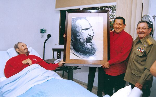 El presidente venezolano Hugo Chávez (centro) sostiene un retrato de Fidel Castro, realizado por el famoso muralista mexicano David Alfaro Siqueiros durante una visita al hospital donde el revolucionario cubano se recuperaba de una cirugía, el 13 de agosto de 2006. - Sputnik Mundo